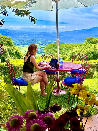 Guest working peacefully from a garden table overlooking the Atenas valley